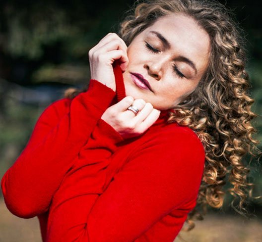 young woman with curly hair and red sweater